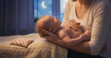 Kobieta masuje brzuszek niemowlęcia okrężnymi ruchami. Obok na łóżku leży termofor z pestek wiśni.