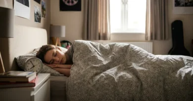 Nastolatka śpiąca spokojnie w łóżku, obok na szafce nocnej stoi budzik.
